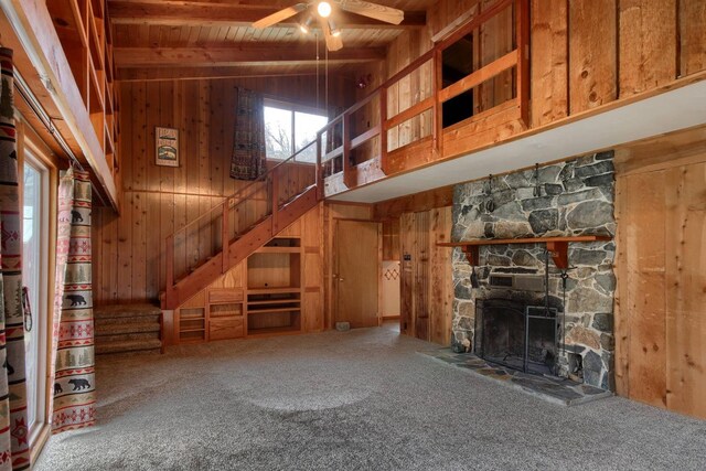 unfurnished living room with wood ceiling, wooden walls, carpet floors, high vaulted ceiling, and beam ceiling