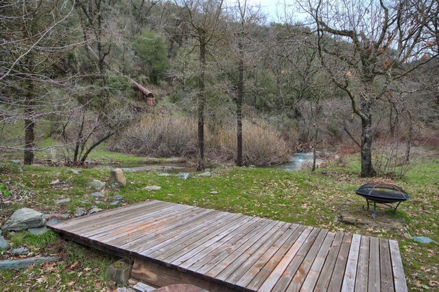 wooden deck with an outdoor fire pit and a yard