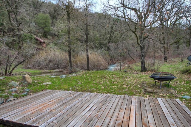 wooden terrace featuring a lawn and an outdoor fire pit