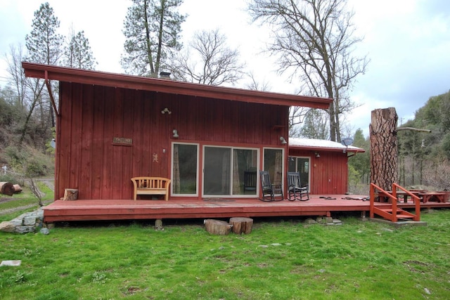 rear view of property featuring a deck and a yard