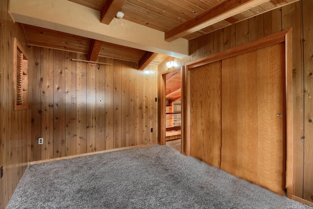 interior space featuring carpet flooring, beamed ceiling, wooden walls, and wooden ceiling