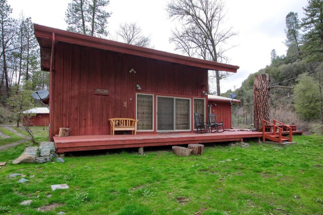 rear view of house featuring a lawn and a deck