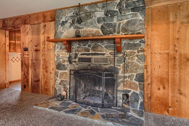 room details featuring a fireplace, carpet, and wooden walls