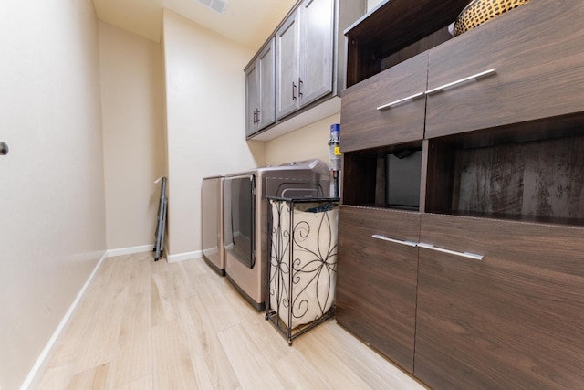 laundry area featuring cabinets, separate washer and dryer, and light hardwood / wood-style floors