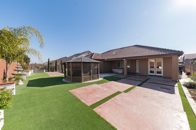 rear view of property with a sunroom, a yard, and a patio