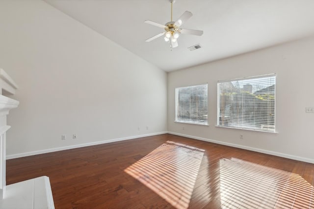 spare room with vaulted ceiling, ceiling fan, dark hardwood / wood-style flooring, and a fireplace