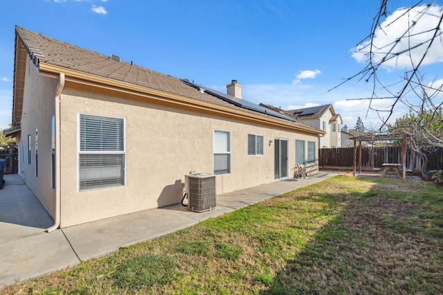 rear view of house with a patio area, central AC unit, a lawn, and solar panels