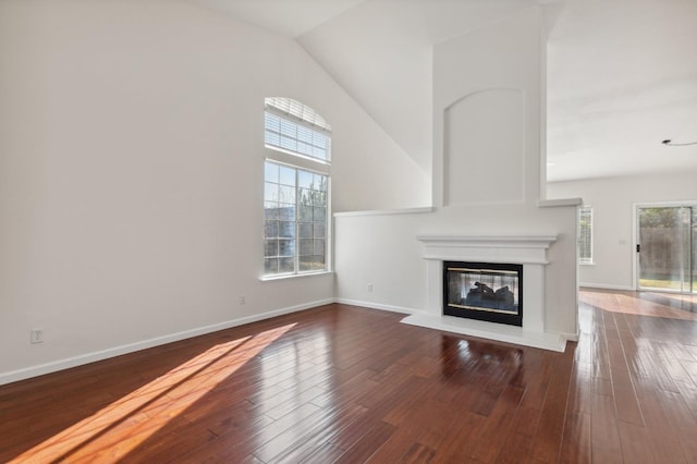 unfurnished living room featuring lofted ceiling, a healthy amount of sunlight, and hardwood / wood-style floors