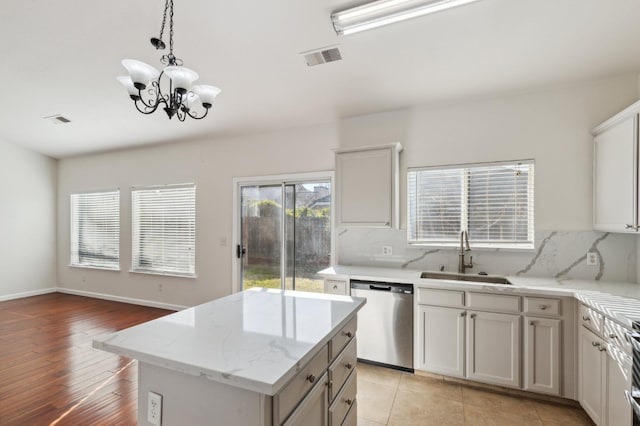 kitchen featuring stainless steel dishwasher, sink, white cabinetry, and a kitchen island