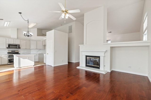 unfurnished living room with high vaulted ceiling, wood-type flooring, and ceiling fan with notable chandelier