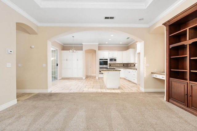 kitchen with light colored carpet, white cabinetry, appliances with stainless steel finishes, and a kitchen island