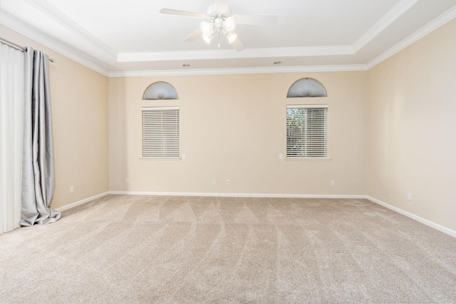 carpeted empty room featuring ceiling fan, ornamental molding, and a raised ceiling