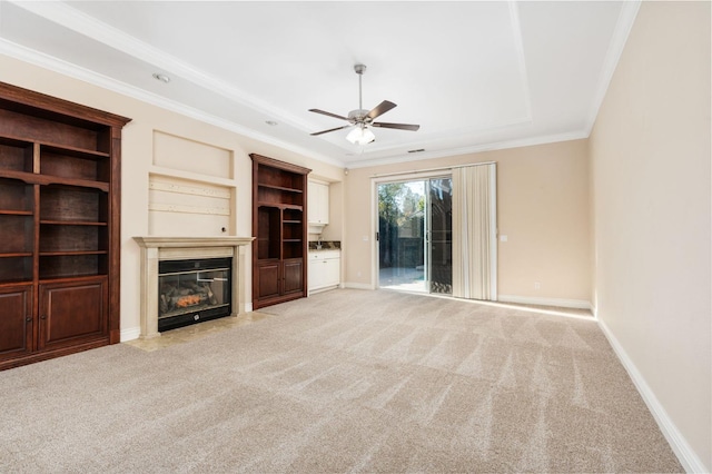 unfurnished living room with ceiling fan, light colored carpet, built in features, and crown molding