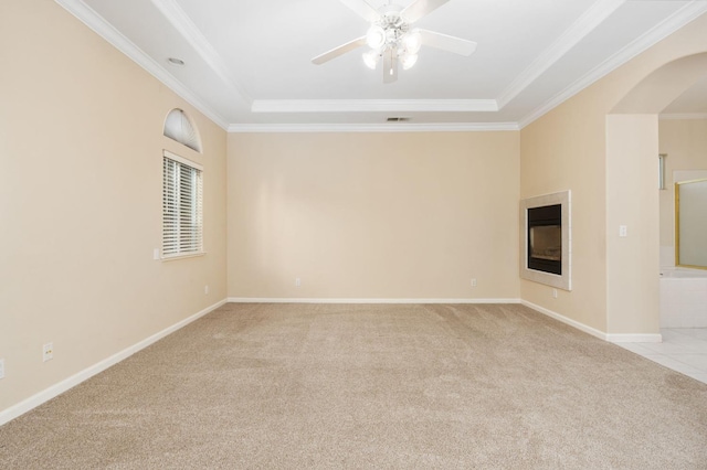 carpeted spare room with ceiling fan, ornamental molding, and a raised ceiling