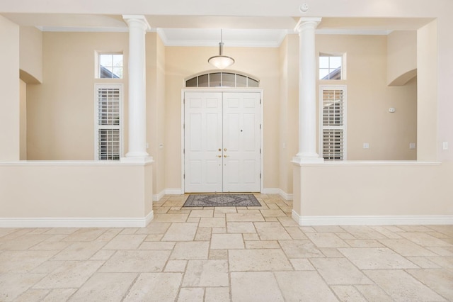 foyer entrance with ornate columns, a wealth of natural light, crown molding, and a towering ceiling