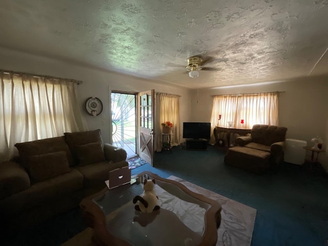 carpeted living room featuring ceiling fan and a textured ceiling