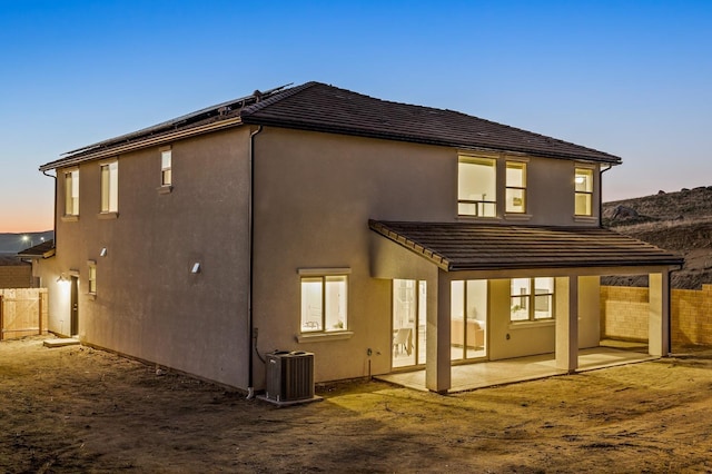 back house at dusk with a patio area and central air condition unit