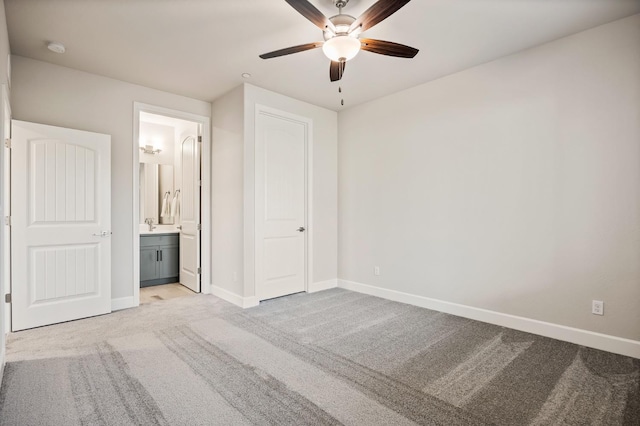 unfurnished bedroom featuring ensuite bathroom, light colored carpet, and ceiling fan