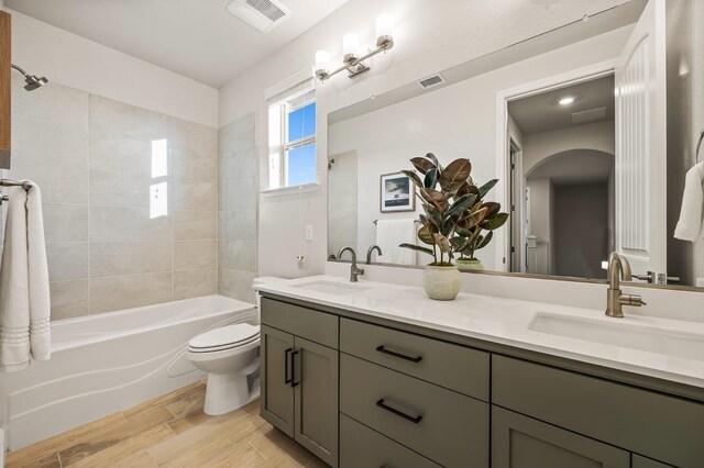 full bathroom with toilet, tiled shower / bath combo, and vanity