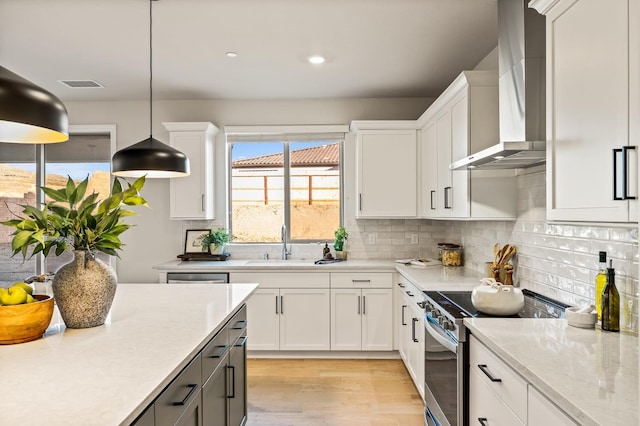 kitchen with hanging light fixtures, white cabinets, stainless steel electric range oven, and wall chimney exhaust hood