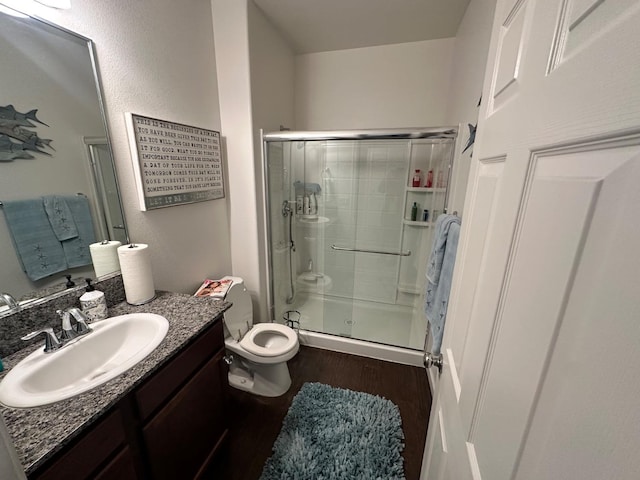 bathroom with hardwood / wood-style floors, toilet, walk in shower, and vanity