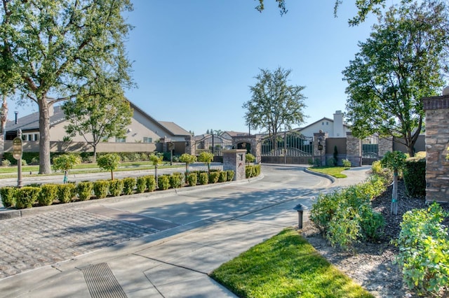 view of street with curbs, a gated entry, and a gate