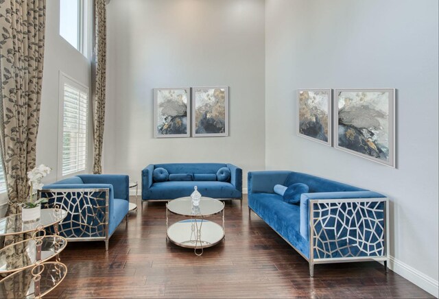 living room featuring wood finished floors, a towering ceiling, and baseboards