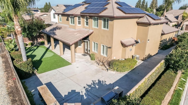 back of property with solar panels, a fenced backyard, a patio, and stucco siding