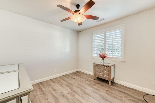 spare room with light wood finished floors, baseboards, visible vents, and ceiling fan