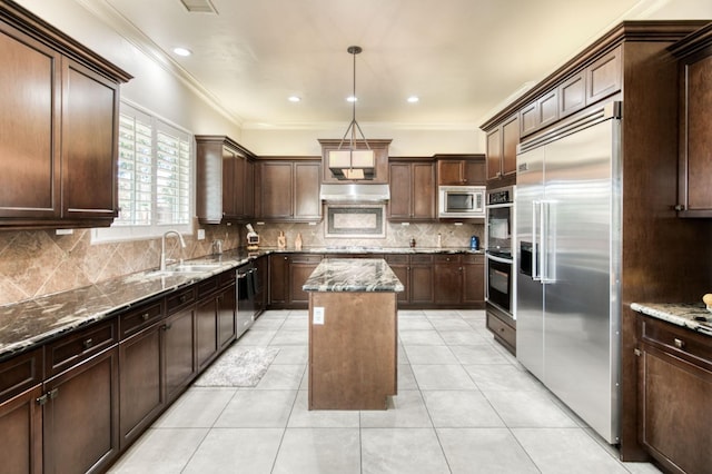 kitchen featuring light tile patterned floors, tasteful backsplash, a kitchen island, dark stone countertops, and built in appliances