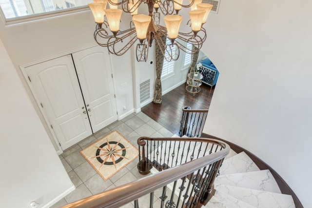 entryway featuring an inviting chandelier, baseboards, visible vents, and tile patterned floors