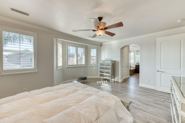 bedroom featuring arched walkways, multiple windows, visible vents, and crown molding