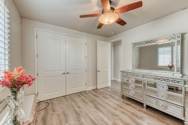 bedroom featuring light wood-type flooring, a closet, ceiling fan, and baseboards