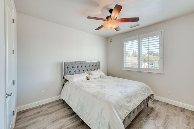 bedroom featuring visible vents, ceiling fan, baseboards, and wood finished floors