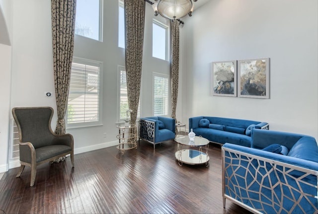 living area with a high ceiling, baseboards, and wood finished floors