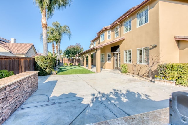 view of front of house with a fenced backyard, a patio, and stucco siding