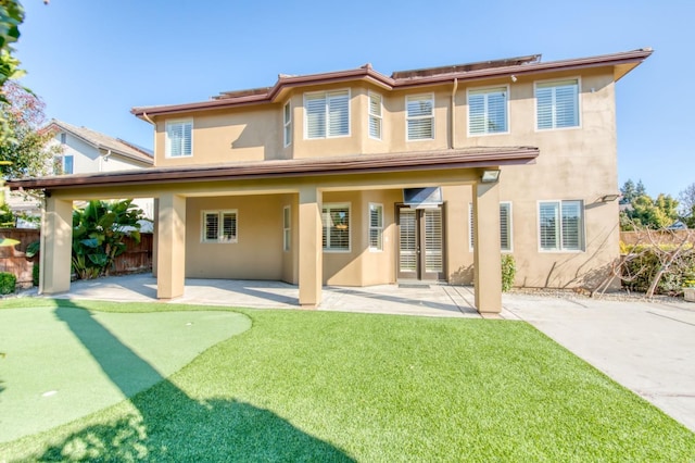 rear view of house featuring a patio area, fence, and stucco siding