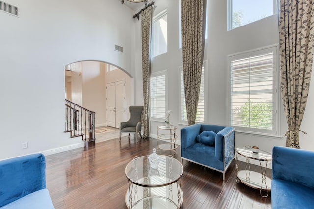 sitting room featuring arched walkways, visible vents, baseboards, and wood finished floors