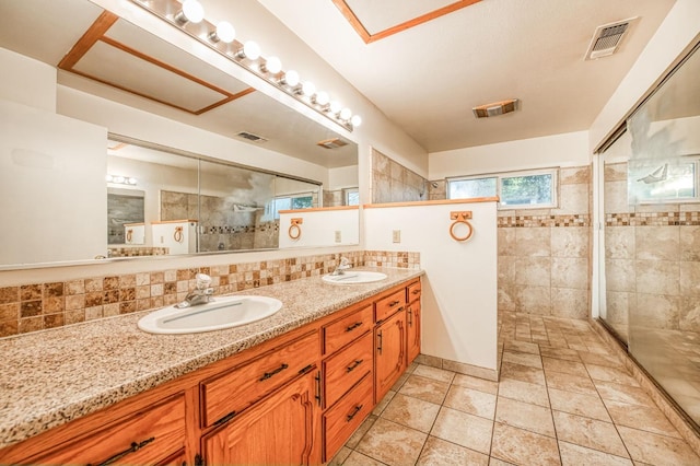 bathroom with vanity, a tile shower, and tasteful backsplash