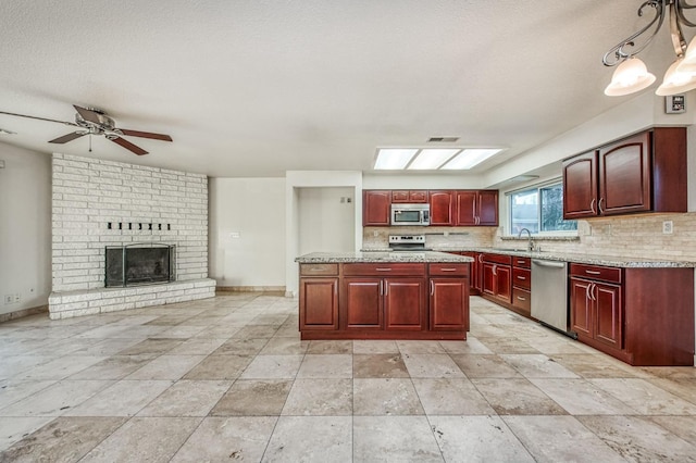 kitchen with a center island, a fireplace, sink, decorative light fixtures, and stainless steel appliances