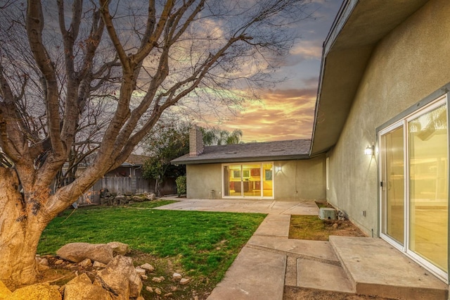 yard at dusk featuring a patio