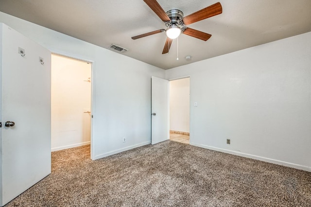 unfurnished bedroom with ceiling fan, light colored carpet, and a walk in closet