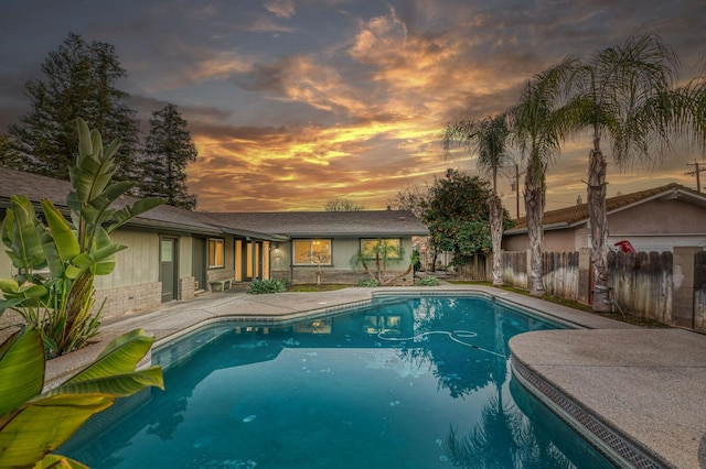 pool at dusk featuring a patio