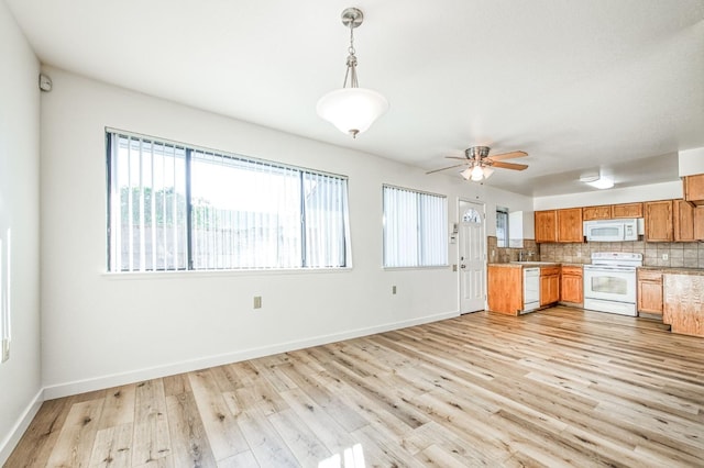 kitchen featuring white appliances, light hardwood / wood-style floors, backsplash, hanging light fixtures, and ceiling fan