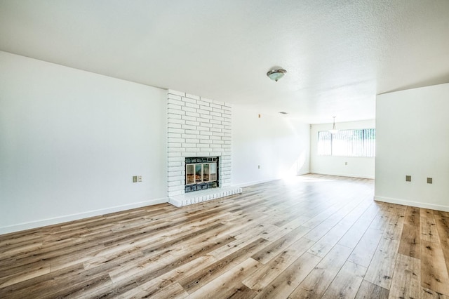 unfurnished living room featuring a brick fireplace and light hardwood / wood-style flooring