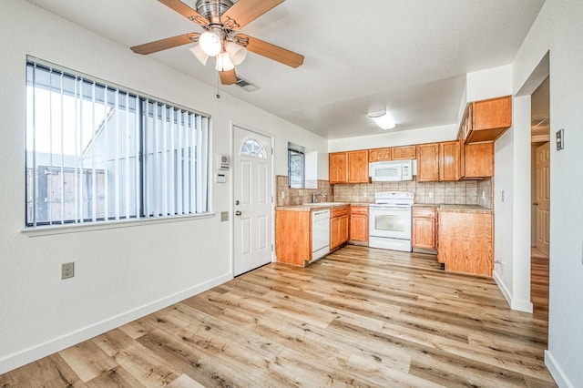 kitchen with light hardwood / wood-style floors, backsplash, white appliances, and sink