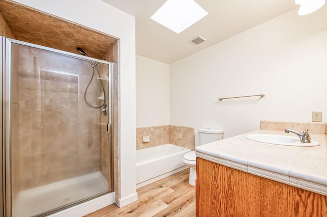 full bathroom with wood-type flooring, toilet, a skylight, and shower with separate bathtub