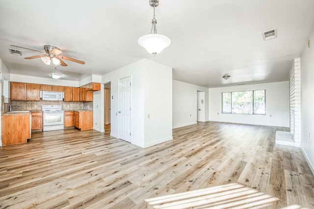 kitchen with white appliances, decorative backsplash, sink, decorative light fixtures, and light hardwood / wood-style flooring