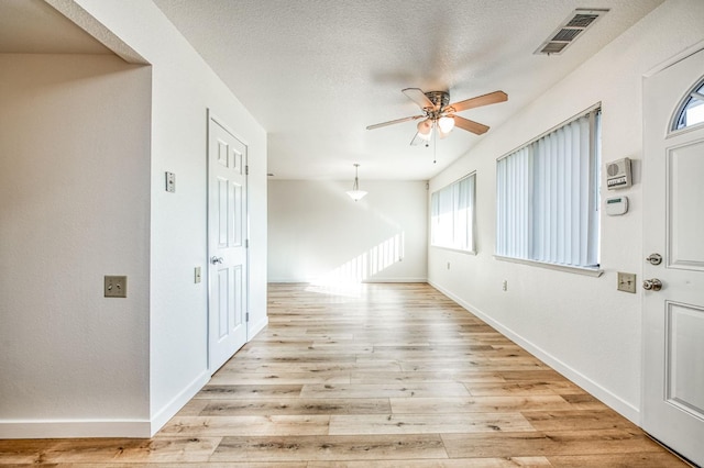 foyer with ceiling fan, light hardwood / wood-style flooring, and a textured ceiling