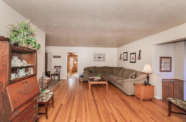 living room with a textured ceiling and light wood-type flooring